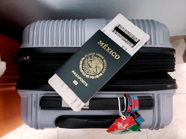 pasaporte mexicano sobre una maleta carry on.